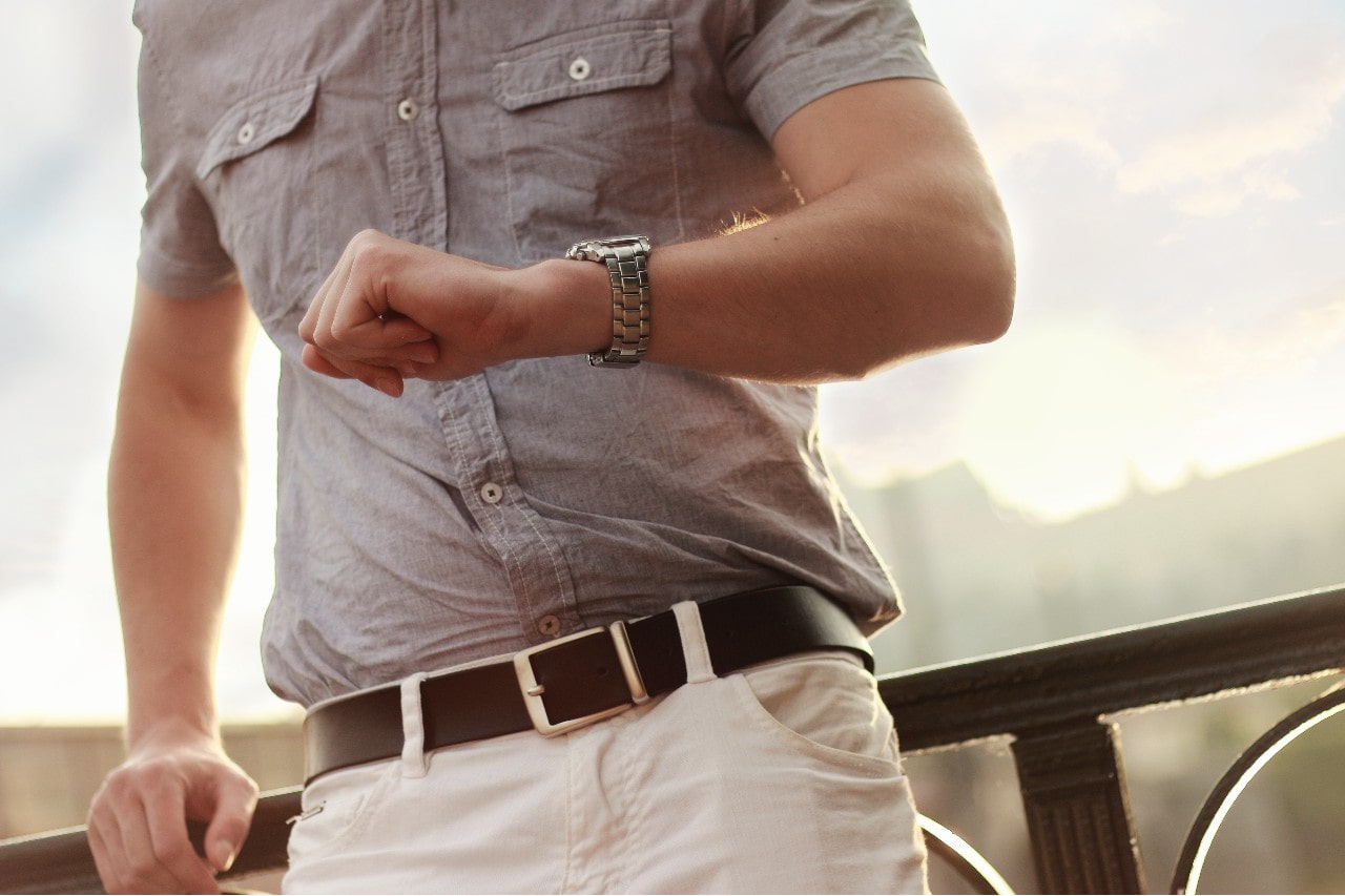 man on rail looking at timepiece