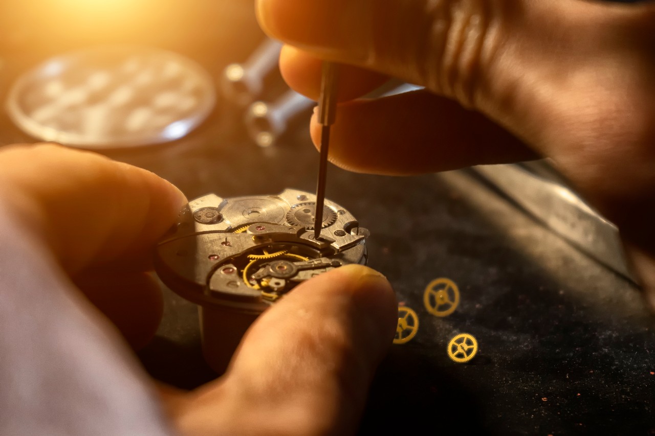 A close-up of a craftsman servicing the inner workings of a wristwatch.