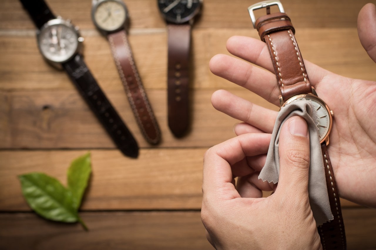 A close-up of a man’s hands as he gently cleans one of his watches.