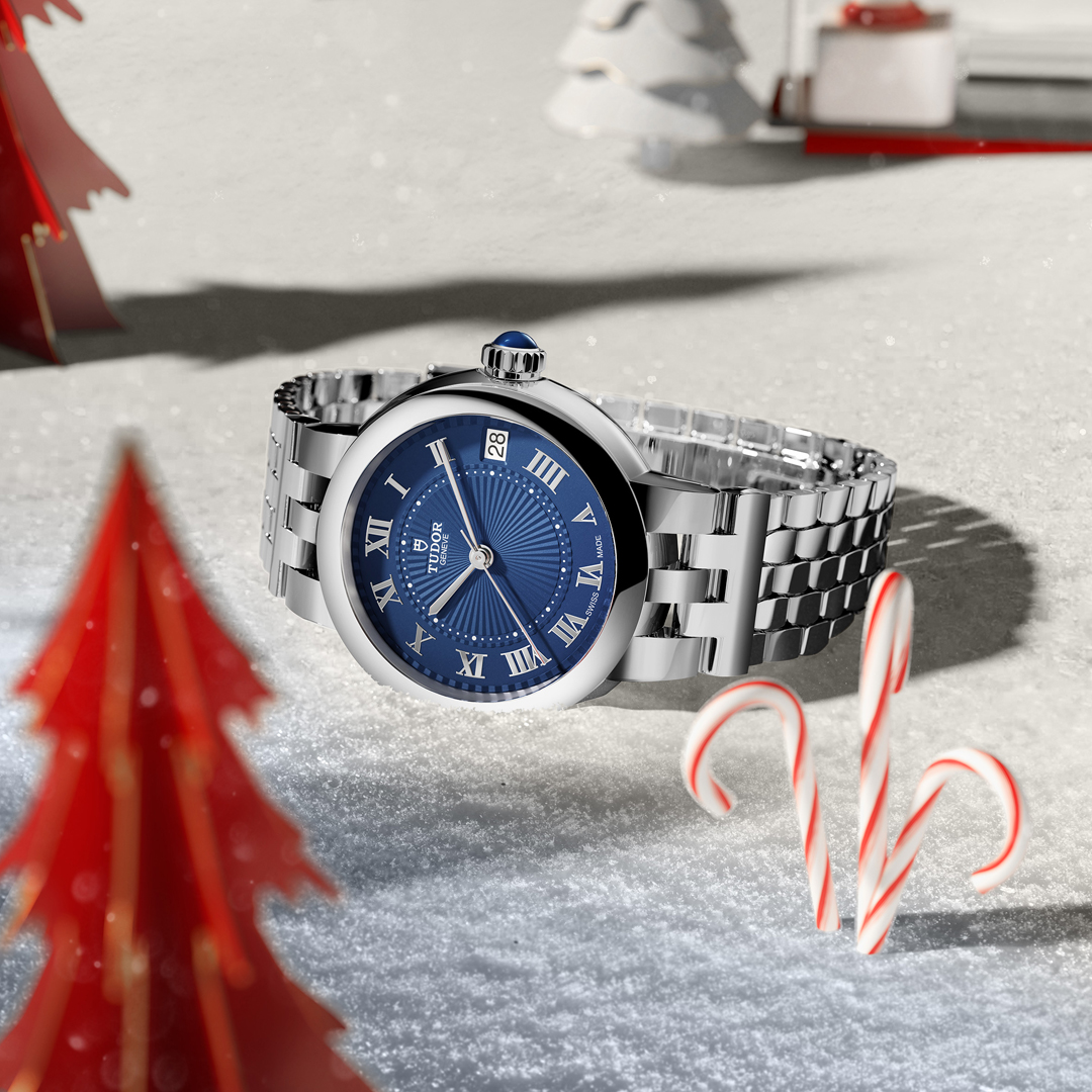 A close-up of a TUDOR Clair de Rose with new ‘TUDOR Blue” dial watch on a festive backdrop.