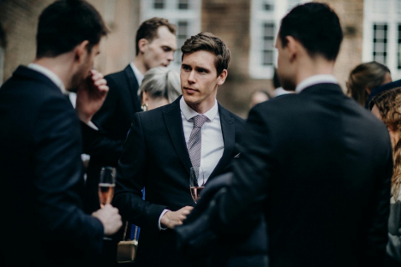 men in suits at a black tie event drinking champagne
