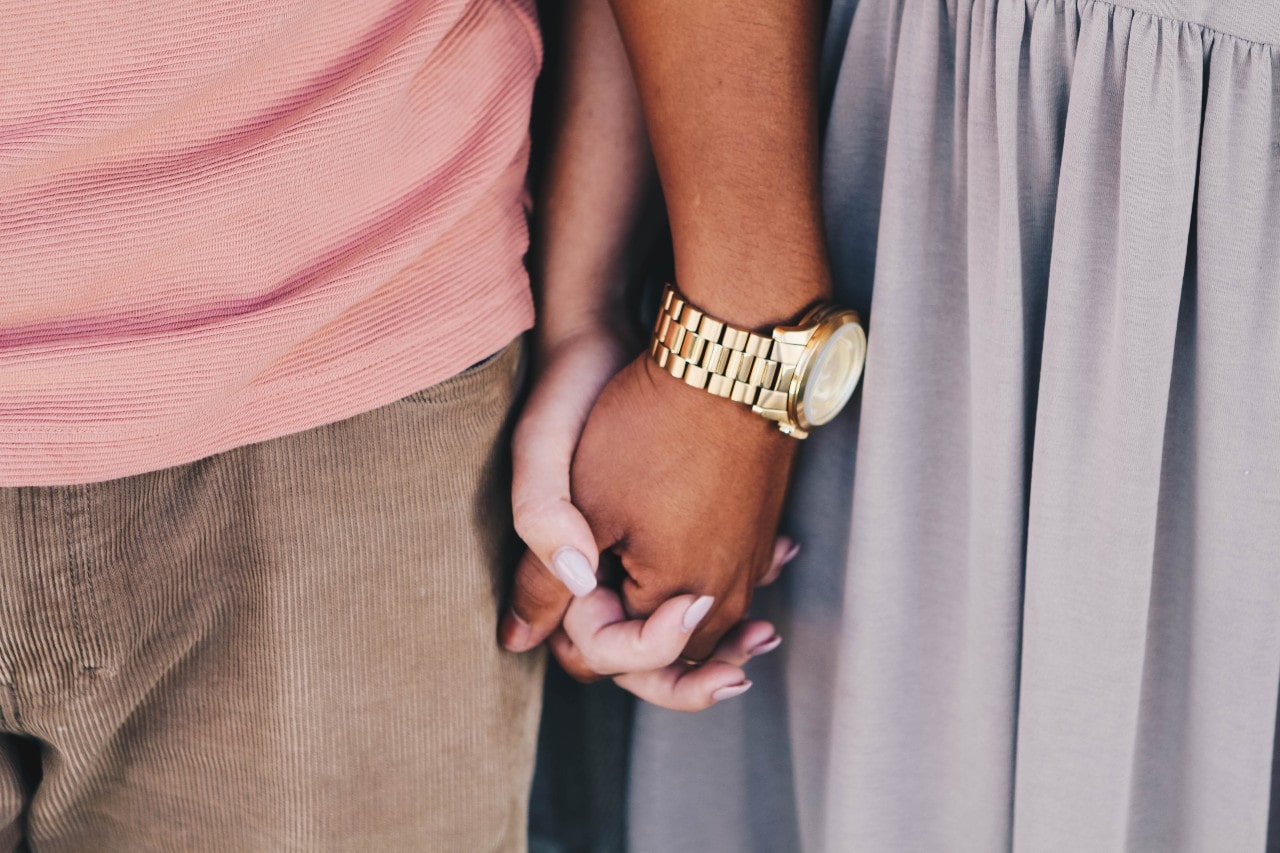 A man with a yellow gold watch holding hands with a woman