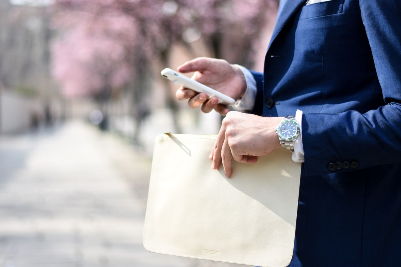 man with watch holding file on phone