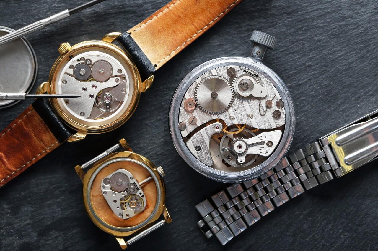 A close-up of three luxury timepieces undergoing routine maintenance.