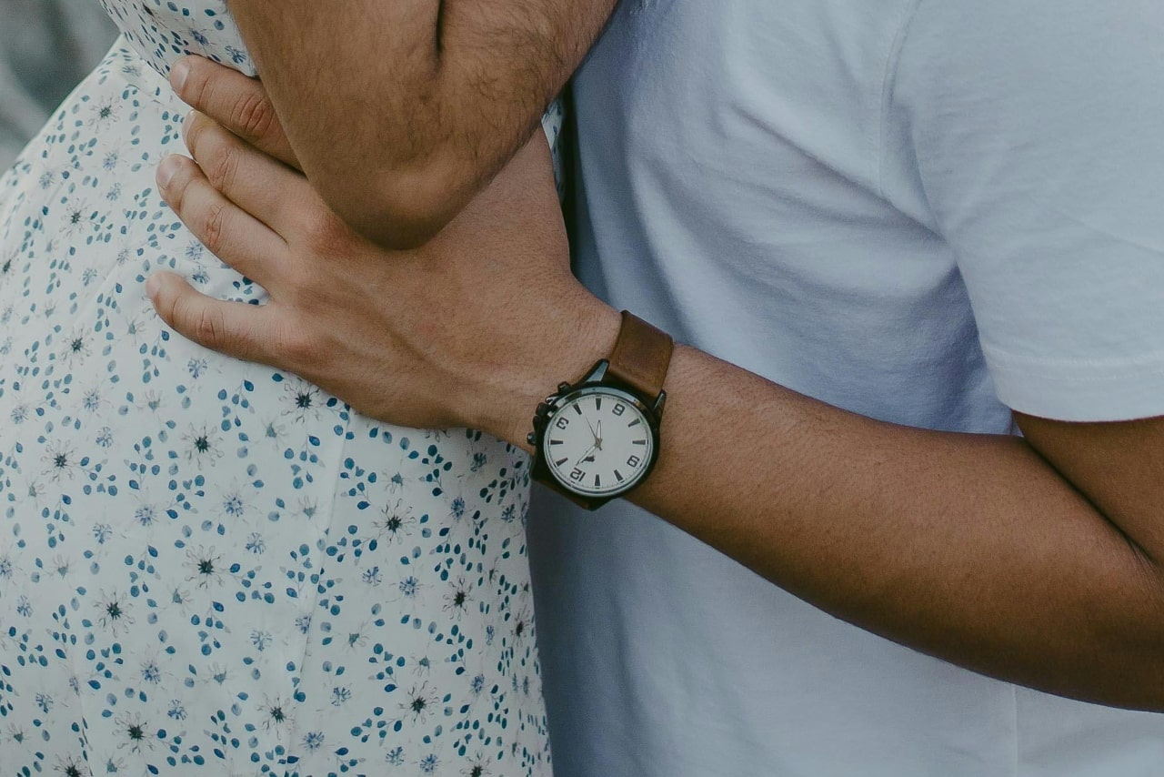 a man holding a woman’s waist and wearing a black and leather watch