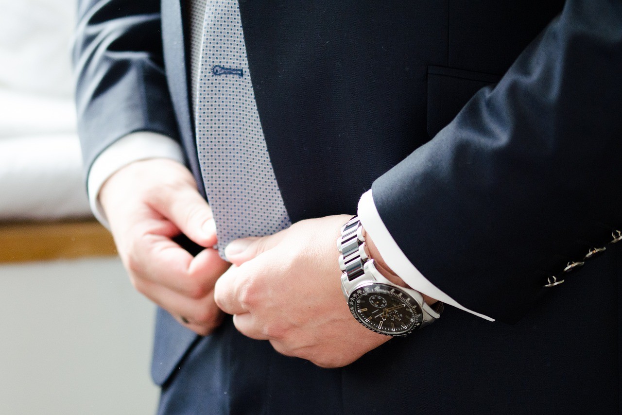 a man adjusting his suit and able to see his silver and black luxury watch